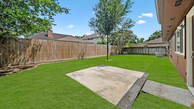 view of yard with central AC and a patio area