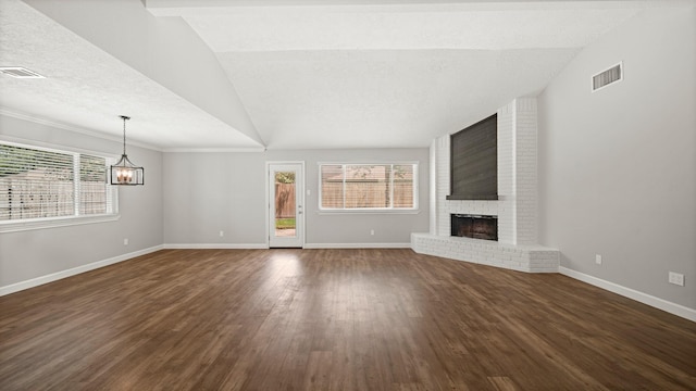 unfurnished living room with dark hardwood / wood-style flooring, a brick fireplace, a textured ceiling, vaulted ceiling, and a chandelier