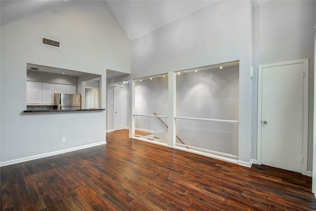 unfurnished living room featuring high vaulted ceiling and dark hardwood / wood-style flooring