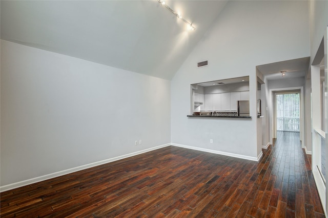 unfurnished living room featuring dark wood-type flooring, rail lighting, and a high ceiling