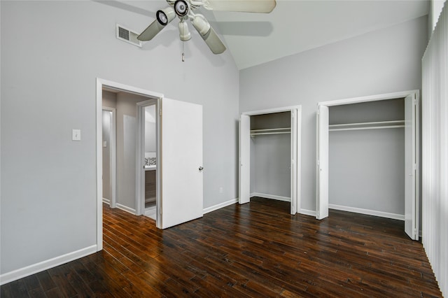 unfurnished bedroom featuring ceiling fan, high vaulted ceiling, dark hardwood / wood-style floors, and two closets