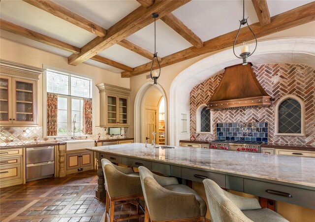 kitchen with light stone countertops, tasteful backsplash, premium range hood, stove, and pendant lighting