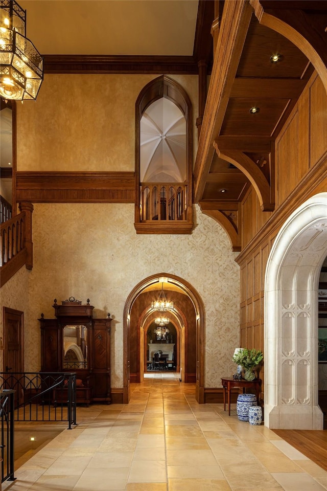 interior space featuring a towering ceiling, crown molding, and an inviting chandelier