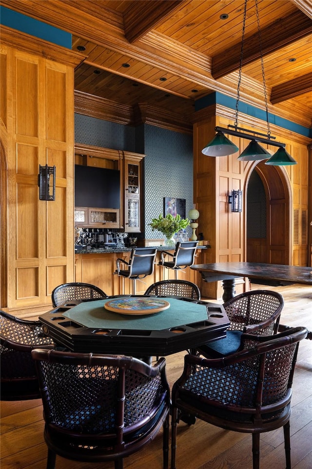 dining area featuring hardwood / wood-style floors, beam ceiling, wooden ceiling, and wooden walls