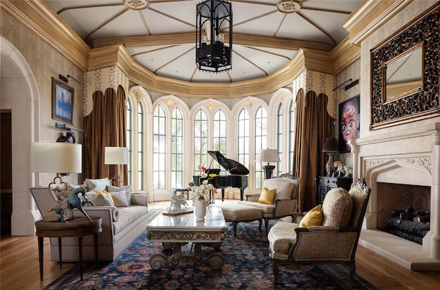 sitting room with a high end fireplace, hardwood / wood-style floors, crown molding, and a high ceiling