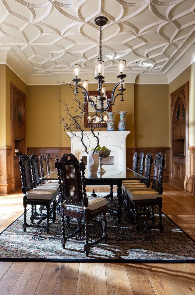 dining space with light hardwood / wood-style floors, a chandelier, coffered ceiling, and ornamental molding