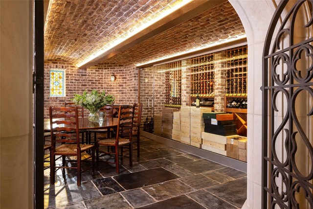 wine room featuring brick ceiling, brick wall, and lofted ceiling