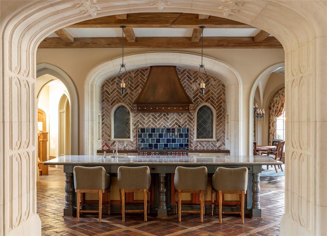 interior space with backsplash, beam ceiling, and sink