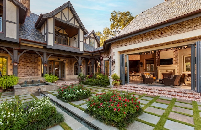 back of house with an outdoor living space with a fireplace, a balcony, and a patio