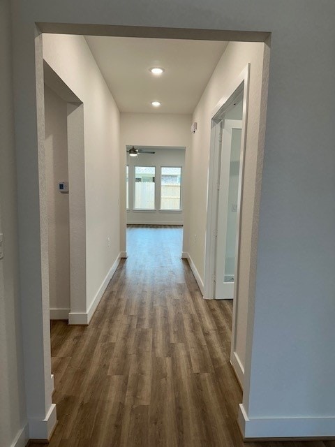 hallway with dark wood-type flooring, recessed lighting, and baseboards