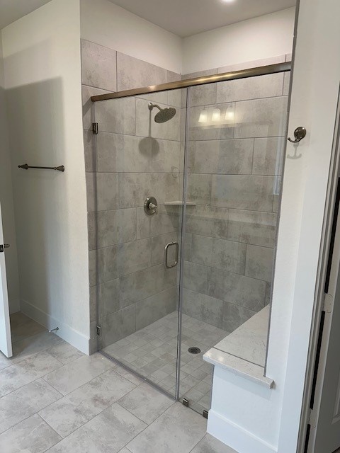 bathroom with a stall shower and baseboards