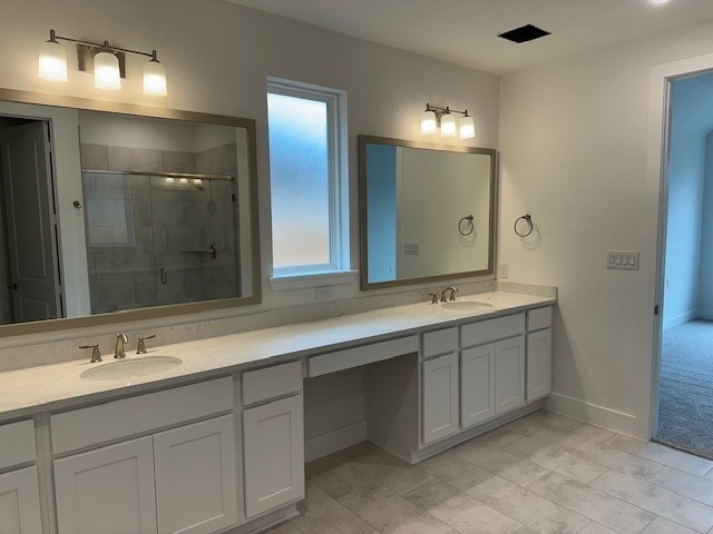 bathroom featuring double vanity, a stall shower, a sink, and baseboards