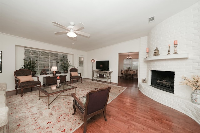 living room featuring a fireplace, hardwood / wood-style floors, ceiling fan with notable chandelier, and vaulted ceiling