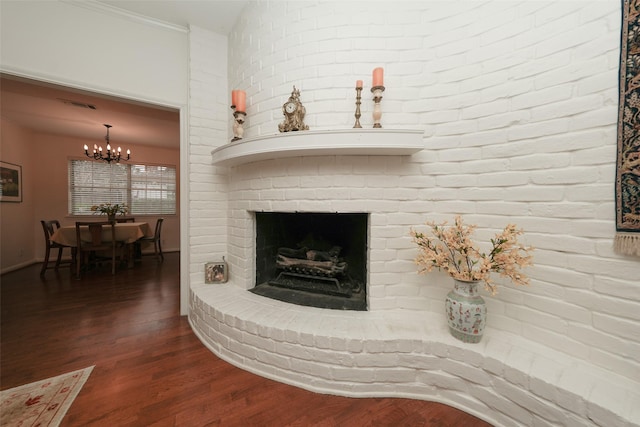 living room featuring an inviting chandelier, ornamental molding, dark hardwood / wood-style floors, and a brick fireplace