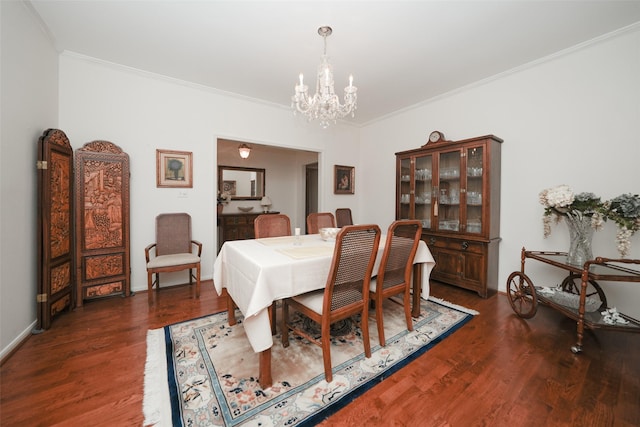 dining area with ornamental molding, dark wood-type flooring, and an inviting chandelier