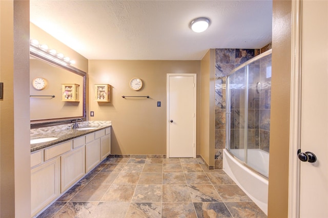 bathroom featuring vanity, bath / shower combo with glass door, and a textured ceiling