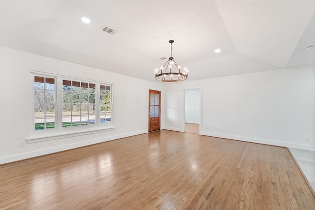 empty room featuring light hardwood / wood-style flooring, an inviting chandelier, and lofted ceiling