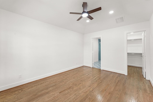 unfurnished bedroom featuring ceiling fan, light wood-type flooring, a closet, and a spacious closet