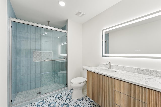 bathroom featuring a shower with shower door, tile patterned floors, toilet, and vanity