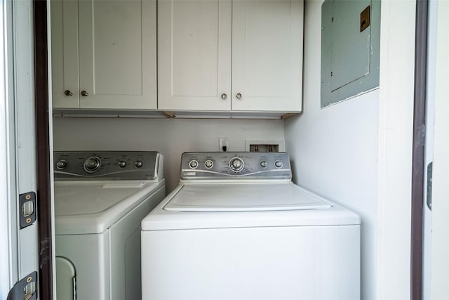 clothes washing area featuring cabinets, washing machine and dryer, and electric panel