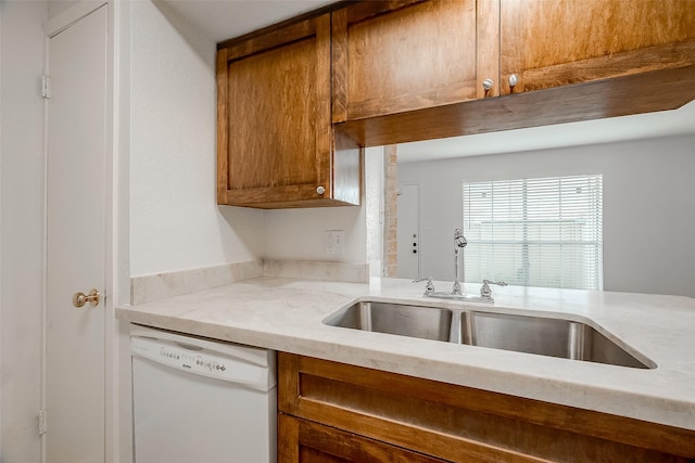 kitchen featuring light stone counters, dishwasher, and sink