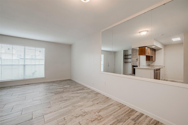 kitchen with kitchen peninsula, light hardwood / wood-style floors, stainless steel dishwasher, and sink