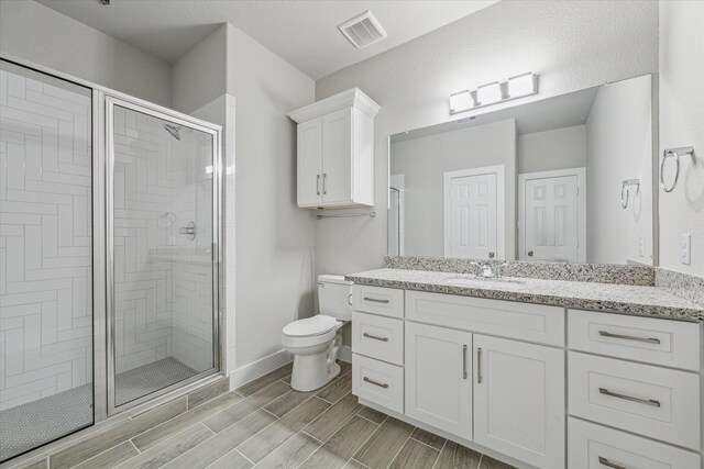 bathroom with vanity, toilet, and a shower with door