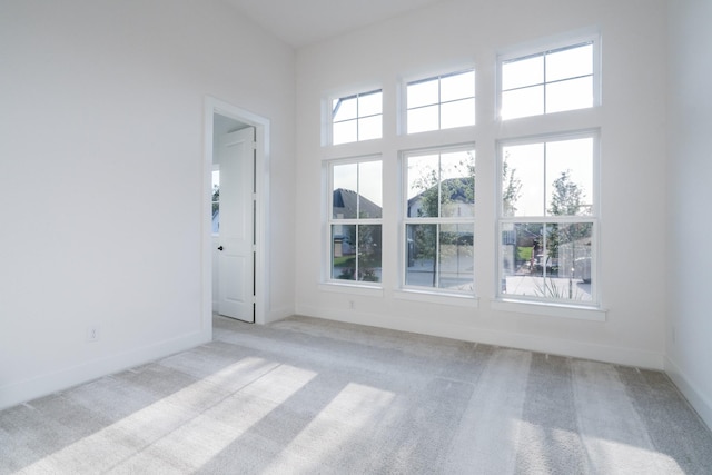 unfurnished room featuring a towering ceiling and light carpet