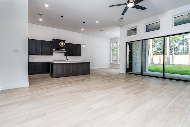 kitchen with a kitchen island with sink, ceiling fan, pendant lighting, and light wood-type flooring