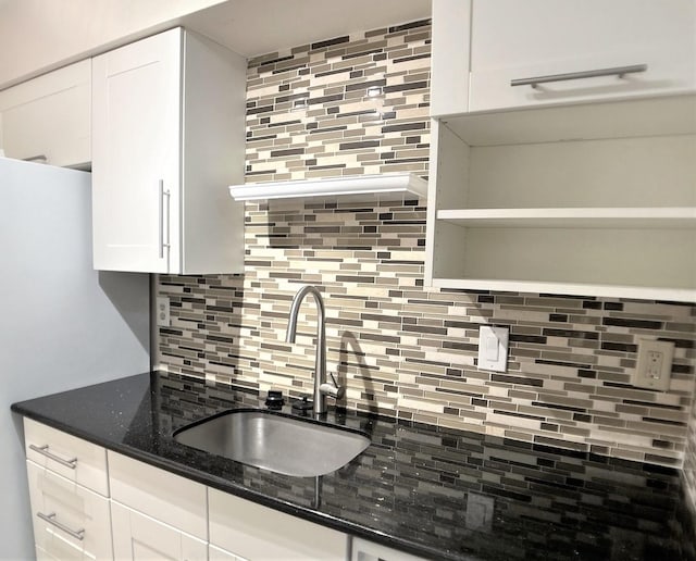 kitchen with white cabinetry, sink, dark stone counters, and tasteful backsplash