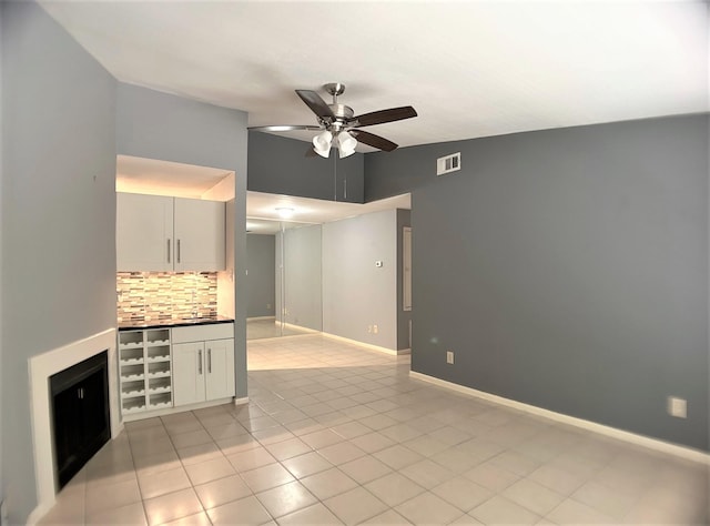 unfurnished living room with sink, ceiling fan, lofted ceiling, and light tile patterned flooring