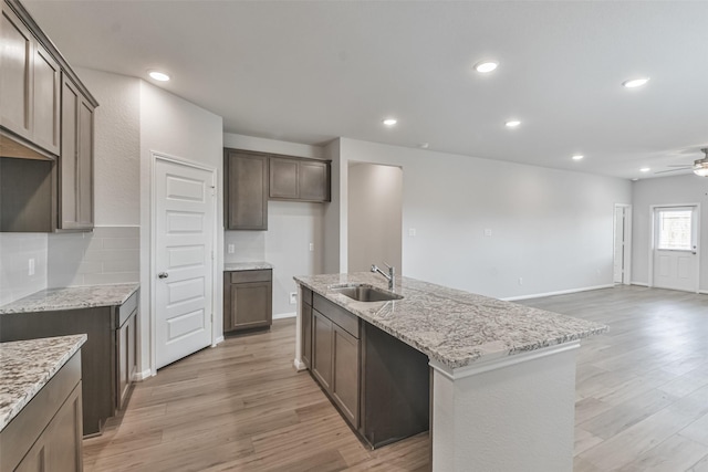 kitchen with ceiling fan, a center island with sink, light wood-type flooring, and sink