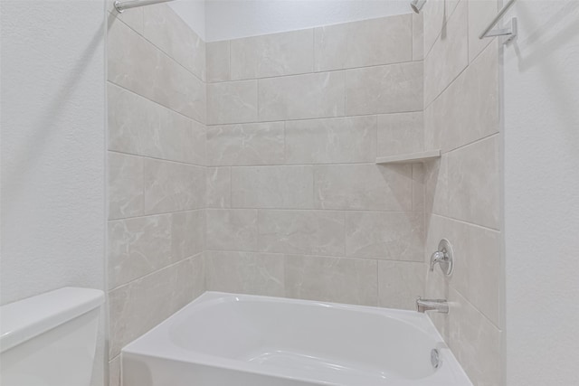 bathroom with toilet and tiled shower / bath