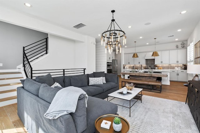 living room with light hardwood / wood-style floors and an inviting chandelier