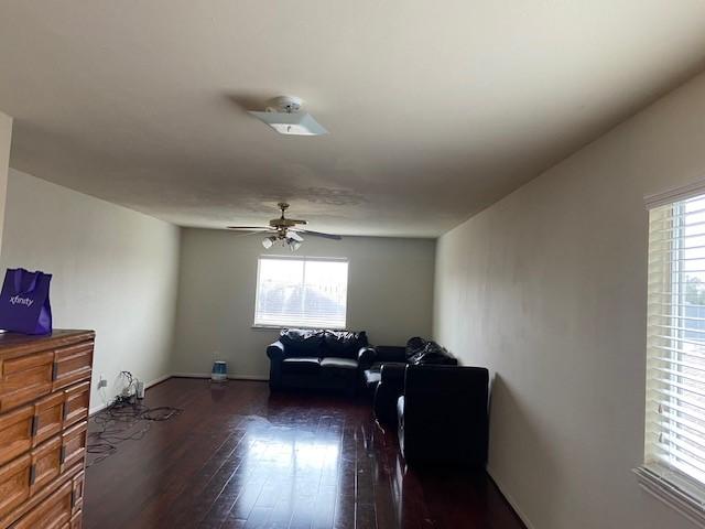 living area with a ceiling fan and dark wood-style flooring