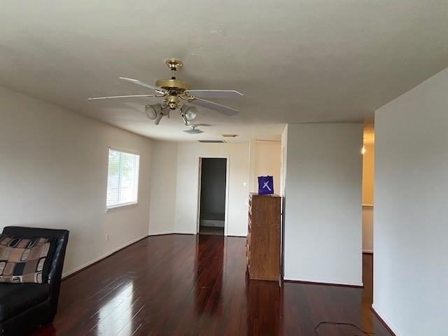 unfurnished room with a ceiling fan and dark wood-type flooring