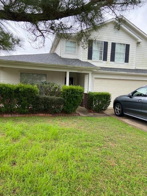 view of front of property featuring an attached garage, driveway, and a front yard