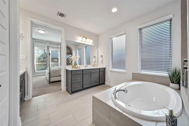 bathroom with tile patterned floors, vanity, and tiled tub