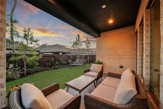 patio terrace at dusk featuring a lawn and an outdoor living space