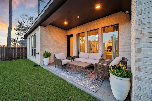 patio terrace at dusk with outdoor lounge area and a lawn