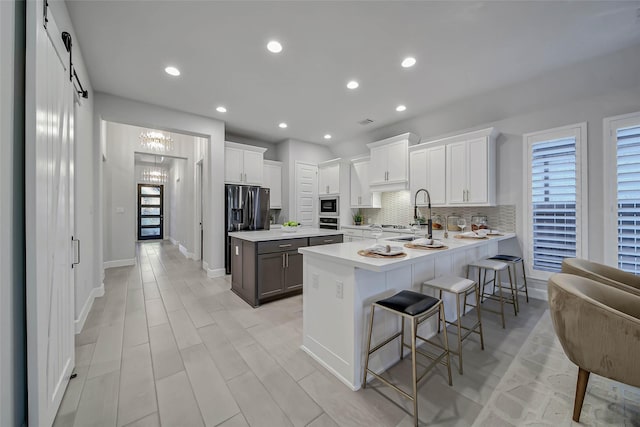 kitchen featuring a kitchen bar, a barn door, kitchen peninsula, and white cabinets