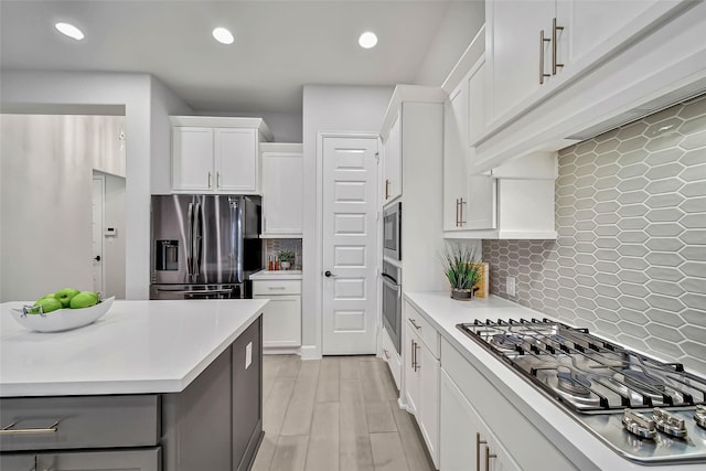 kitchen featuring tasteful backsplash, white cabinets, light hardwood / wood-style floors, and appliances with stainless steel finishes