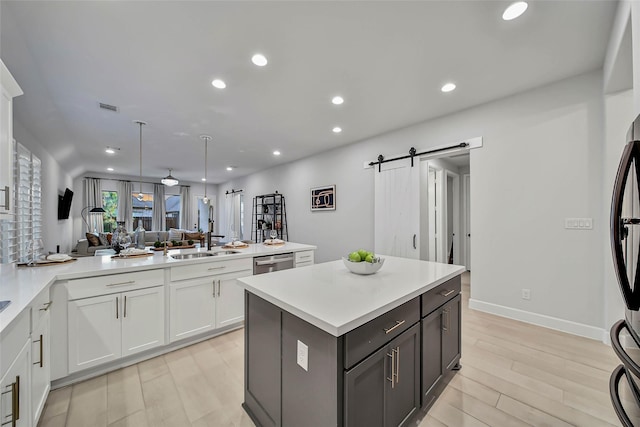 kitchen featuring dishwasher, a center island, sink, a barn door, and white cabinetry