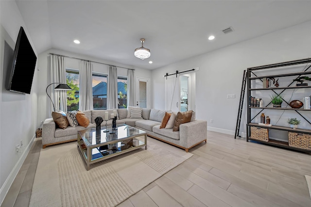 living room with a barn door and light hardwood / wood-style flooring