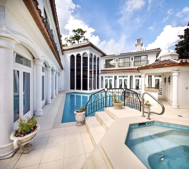 back of house featuring a patio area, sink, and a hot tub