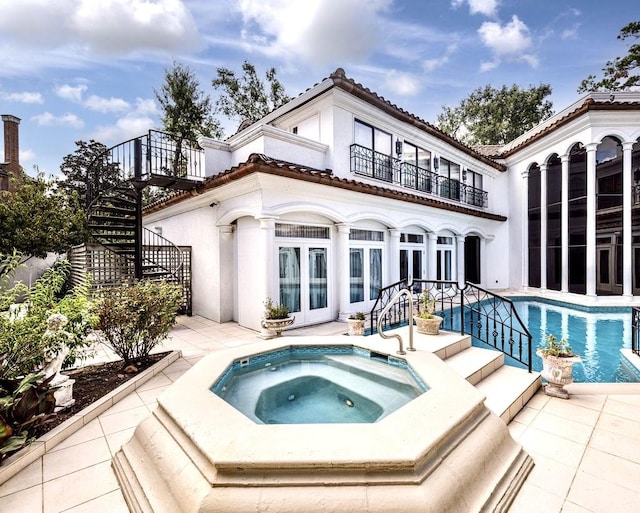 rear view of house featuring an in ground hot tub, a balcony, and sink