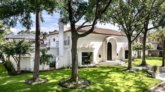 mediterranean / spanish-style home with a balcony and a front lawn