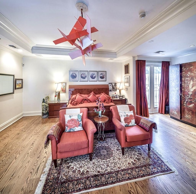 bedroom featuring a raised ceiling, ornamental molding, and light hardwood / wood-style flooring