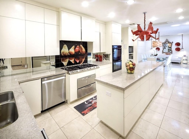 kitchen featuring light stone countertops, white cabinetry, stainless steel appliances, a chandelier, and light tile patterned floors