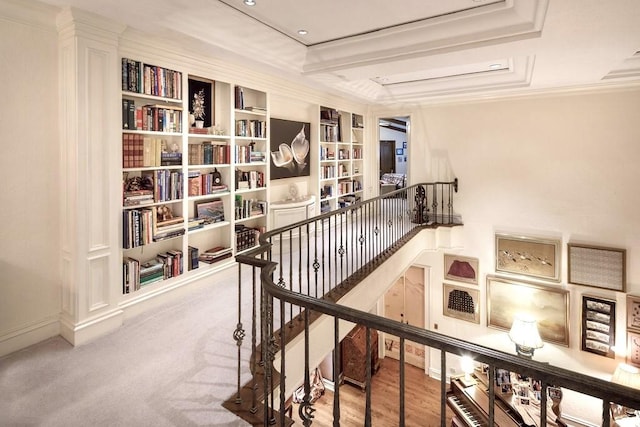 corridor with light carpet, built in shelves, and ornamental molding